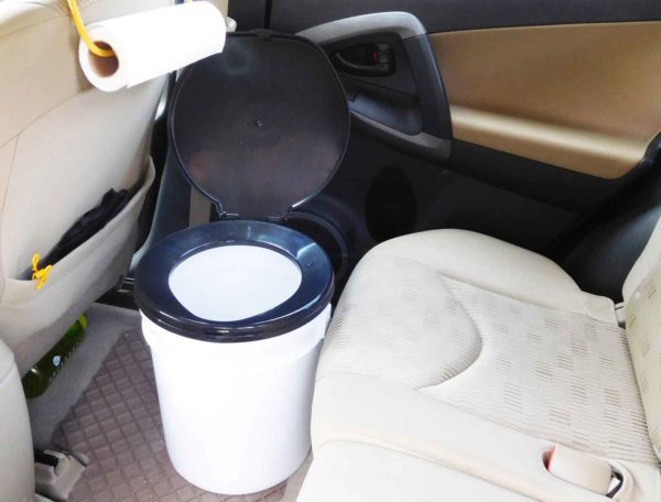 A bucket toilet inside of an SUV