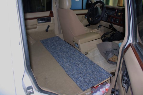 Bridging the gap: the space between the front and rear seats is covered with a simple plank and strip of carpet (a scavenged scrap from a local flooring outlet).