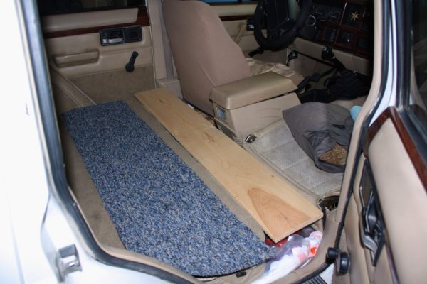 Bridging the gap: the space between the front and rear seats is covered with a simple plank and strip of carpet (a scavenged scrap from a local flooring outlet).