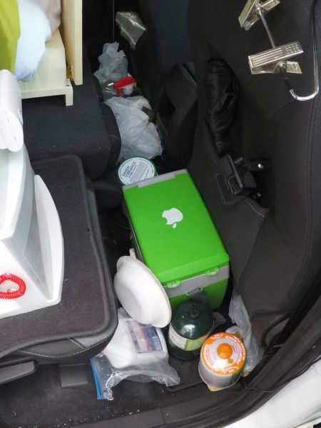 The cooler, stove fuel, and shoes stored on the floor behind the front passenger seat.